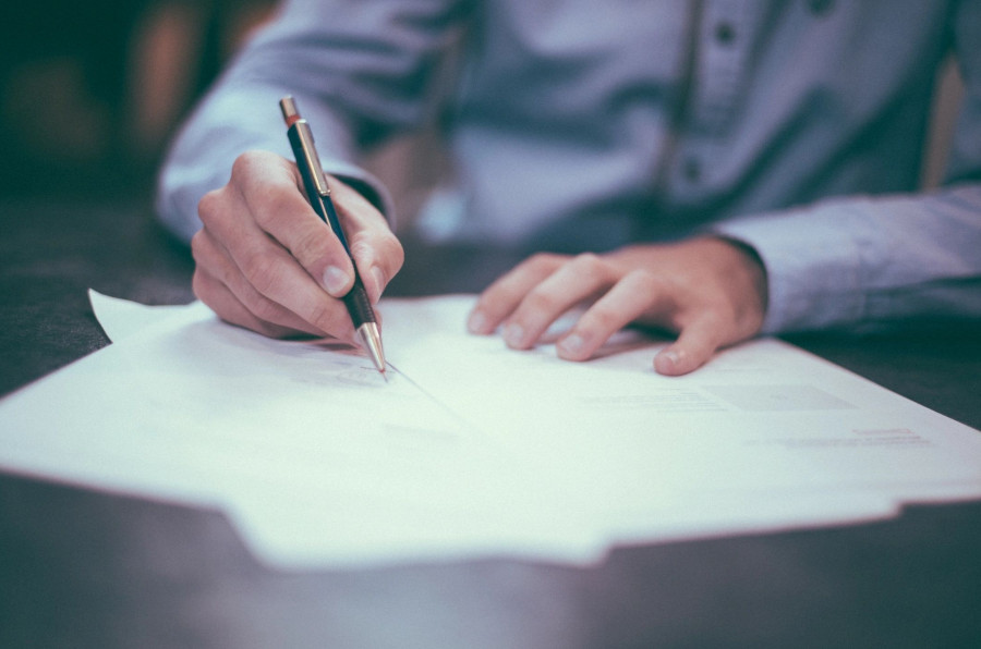 A person writing on paper with a pen.